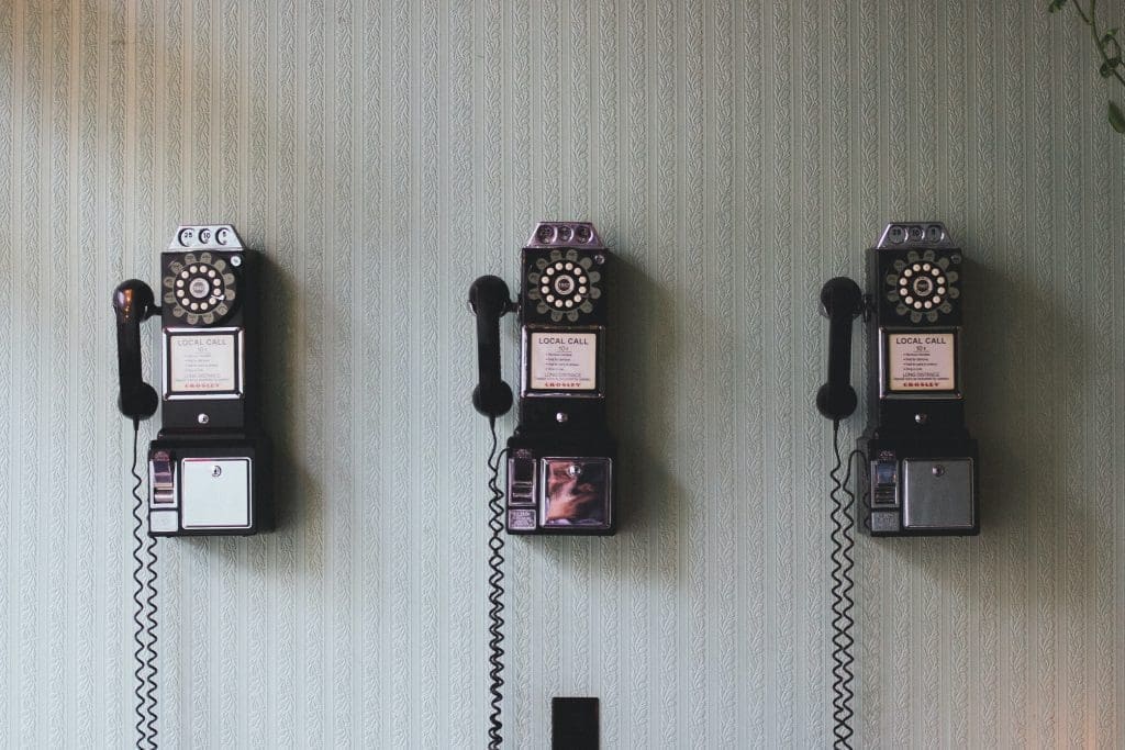 three old cable phones on the wall